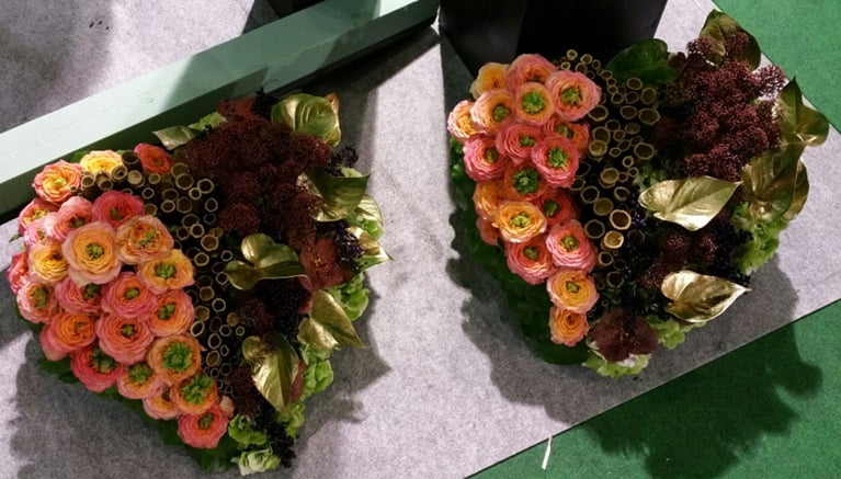 Two heart shaped arrangements with pink flowers, red and gold foliage, and bamboo made with black OASIS® Floral Foam.