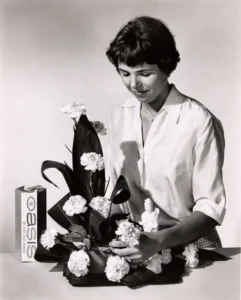 A black and white photo of a female florist assembling a floral arrangement in OASIS® Floral Foam.