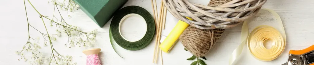 Flowers, OASIS® Floral Foam, florist's tape, twine, florist's knives, shears, and other florist's tools lie together on a table.